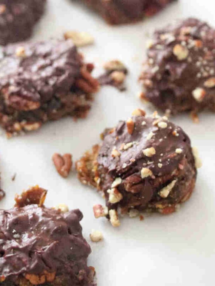 Homemade chocolate pecan turtles on parchment paper.