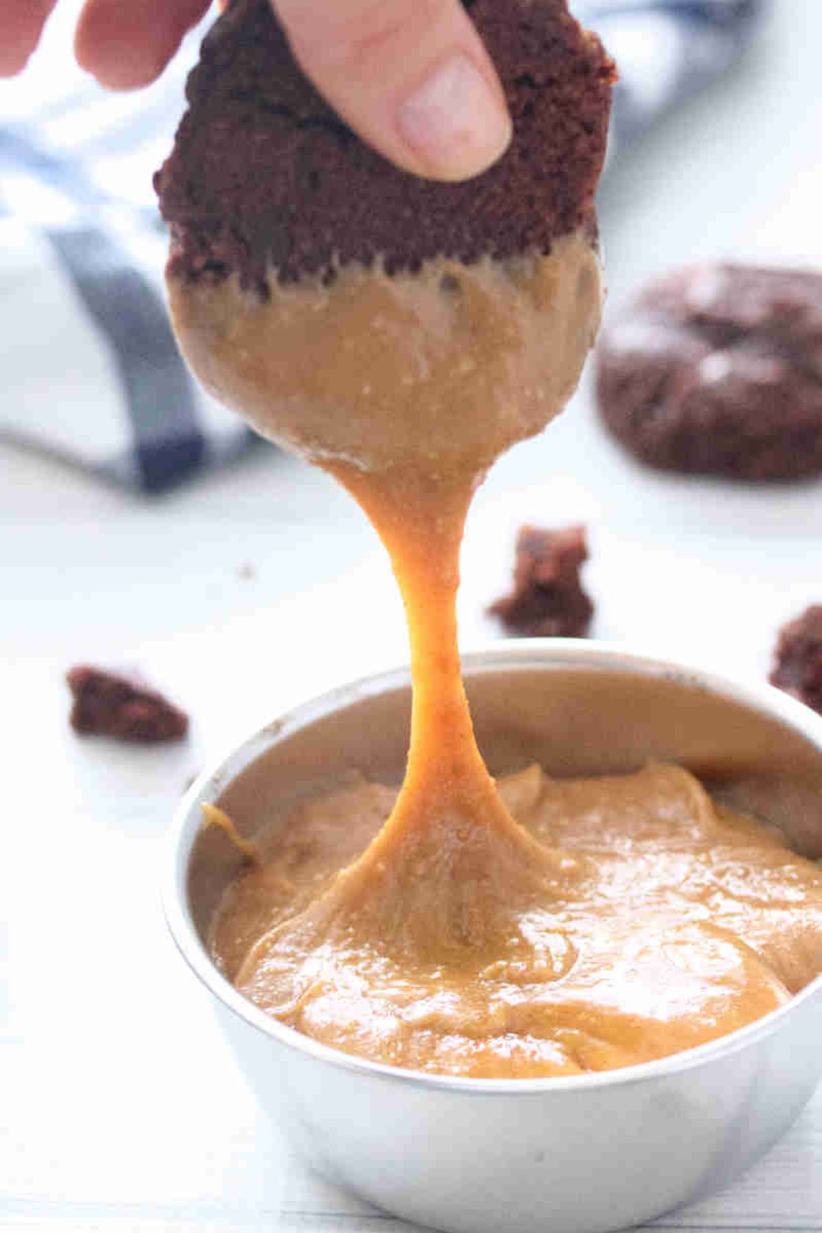 Chocolate cookie being dipped into a bowl of homemade protein cookie butter.