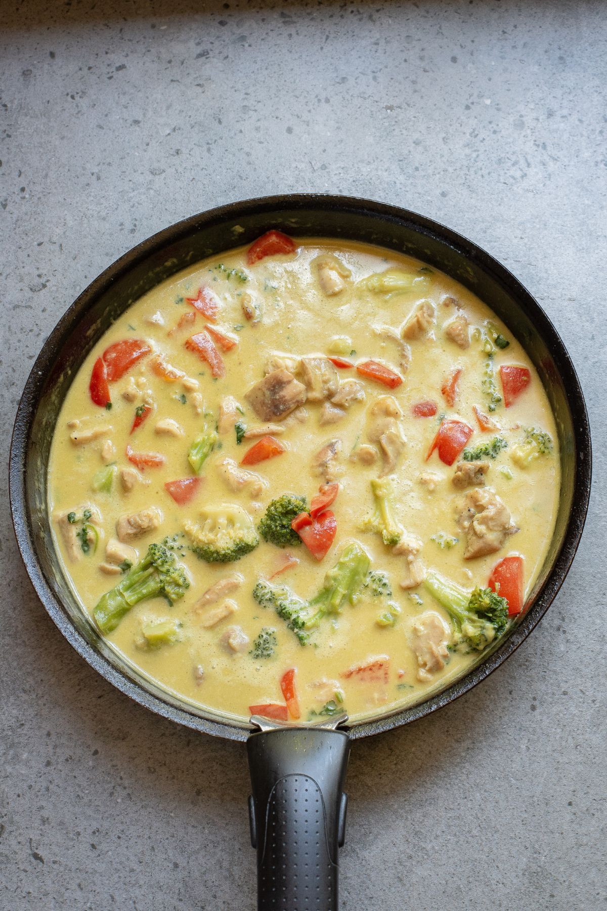Green chicken curry with pineapple and peppers in a skillet.