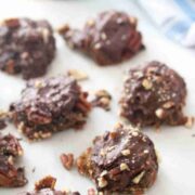 Homemade chocolate turtles with pecans on parchment paper.