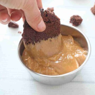 Chocolate cookie being dipped into a bowl of homemade protein cookie butter.