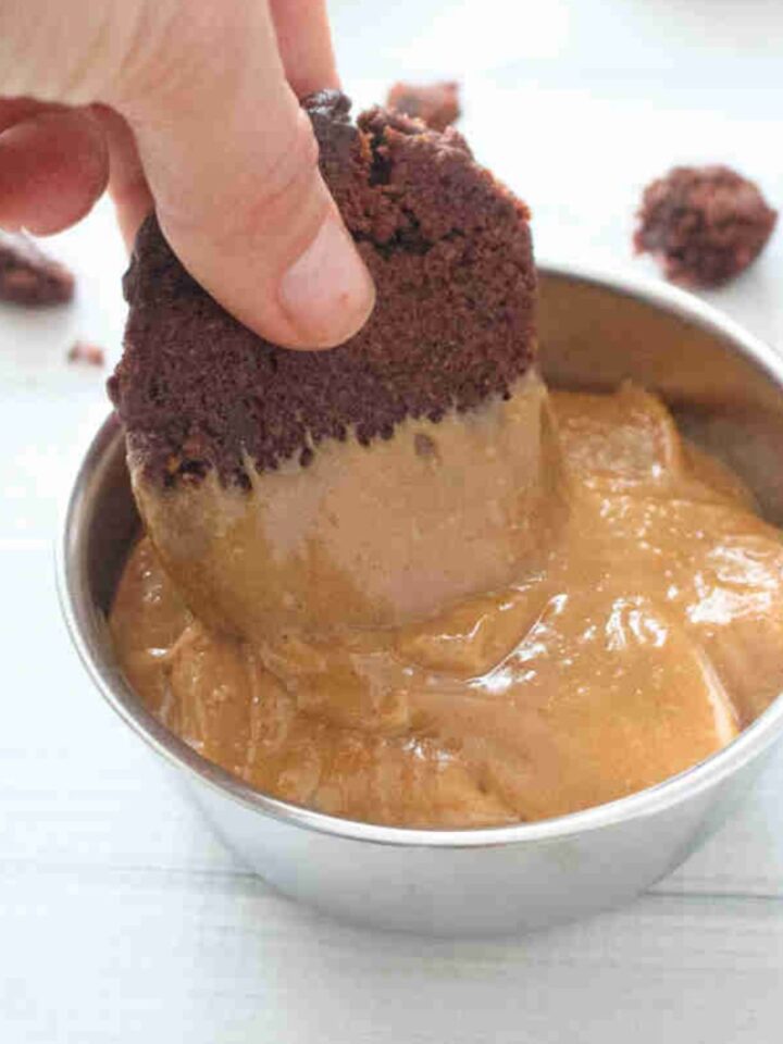 Chocolate cookie being dipped into a bowl of homemade protein cookie butter.