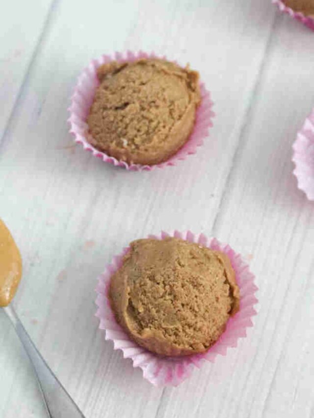 chocolate peanut butter protein balls with a spoonful of peanut butter at the side