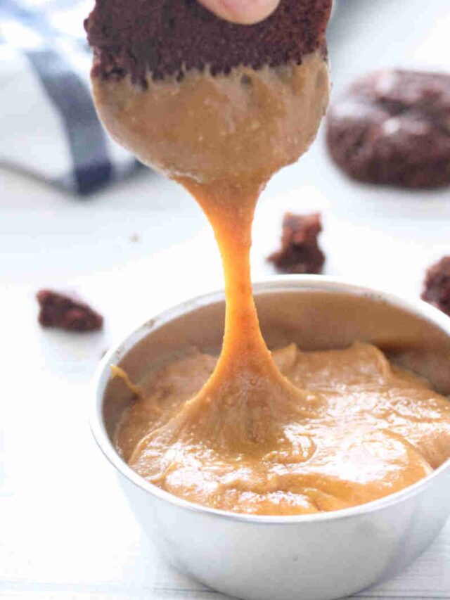 Chocolate cookie being dipped into a bowl of homemade protein cookie butter.