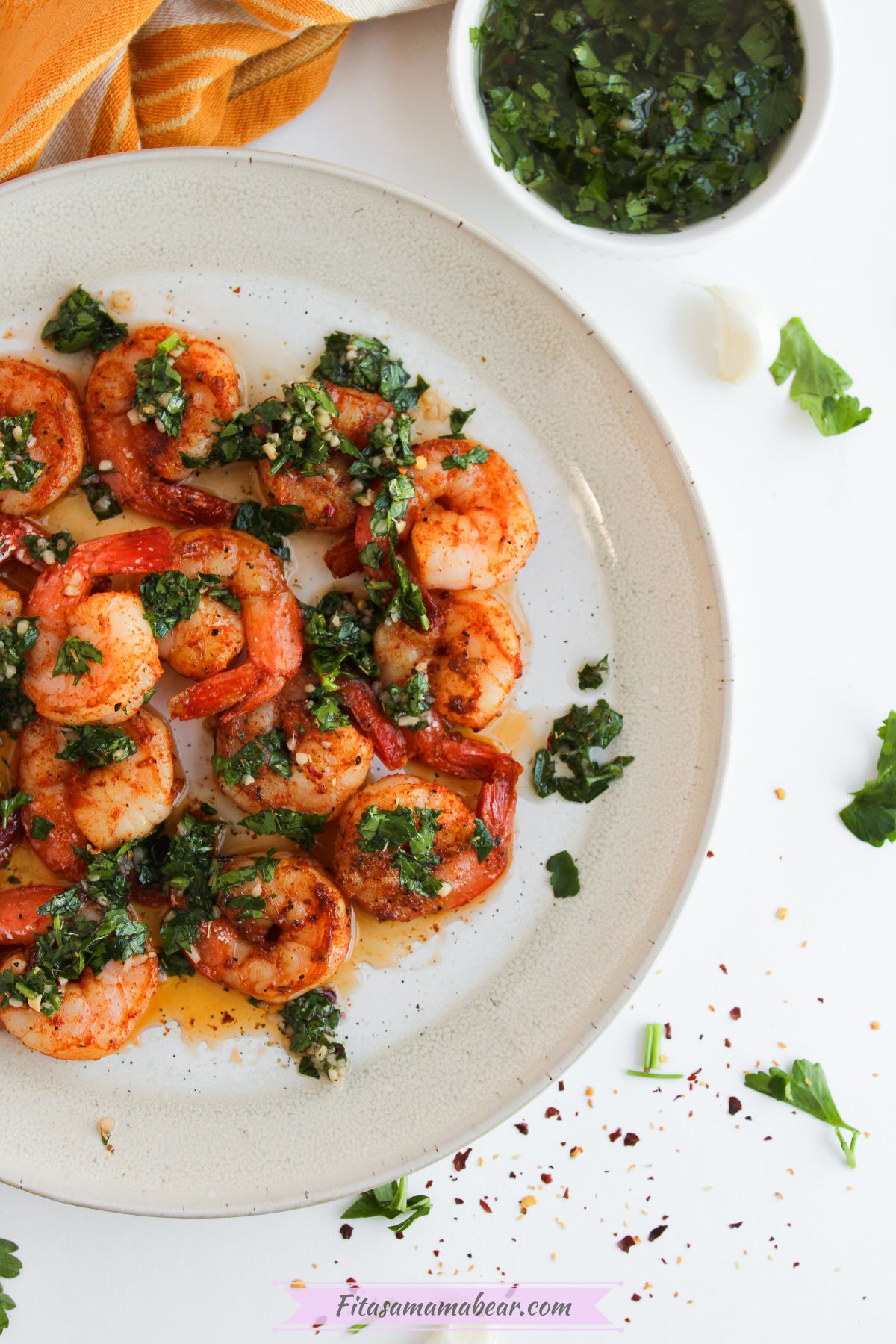 chimichurri shrimp on a white plate with a bowl of chimichurri sauce on the side