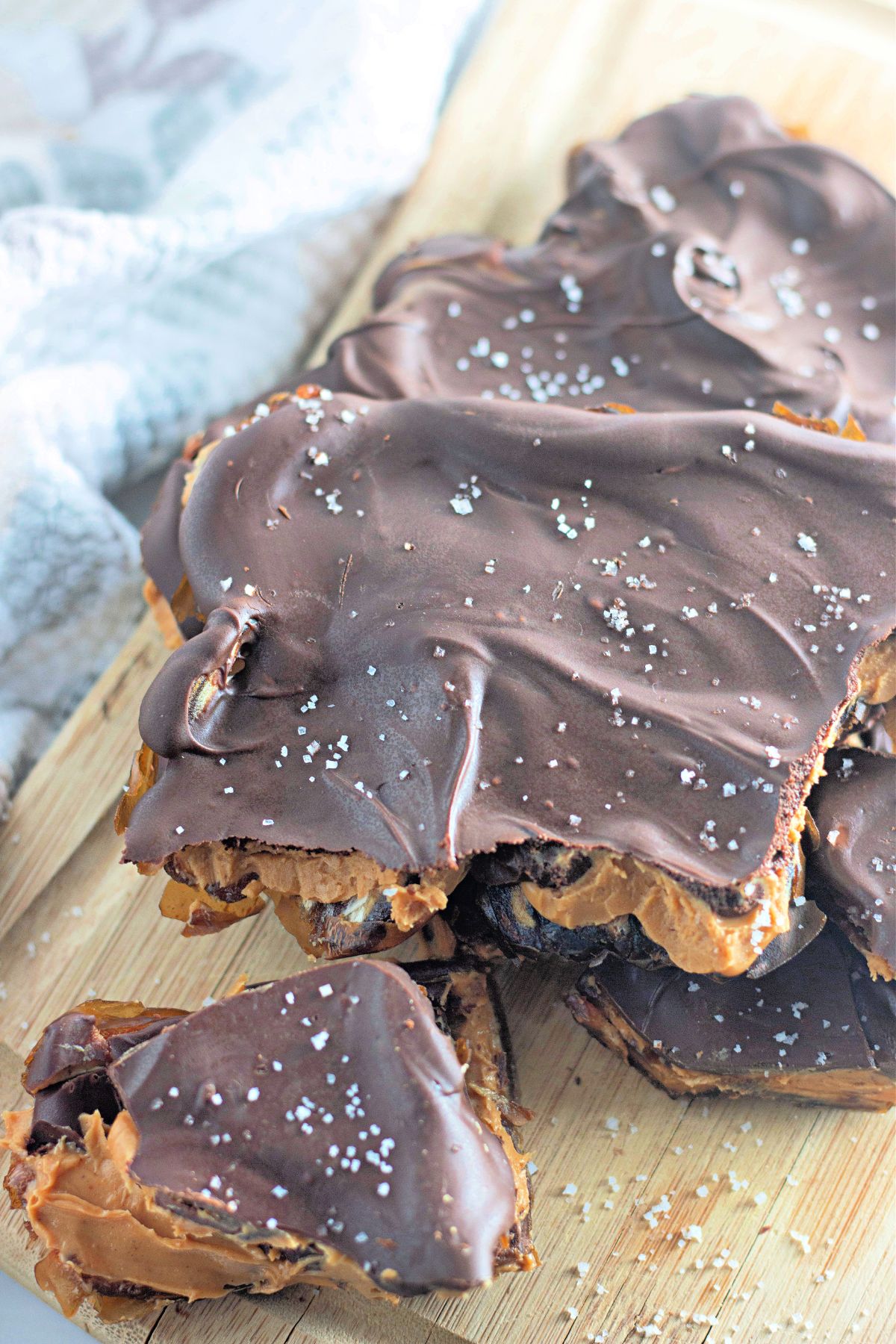 Broken pieces of peanut butter chocolate date bark on a wooden board.