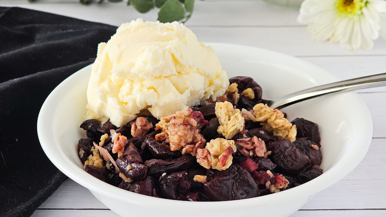 a bowl of cherry granola crisp with a scoop of ice cream