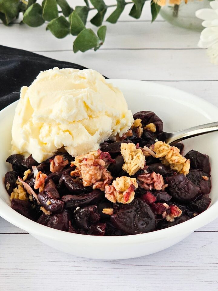 A bowl of cherry crisp with a scoop of ice cream.