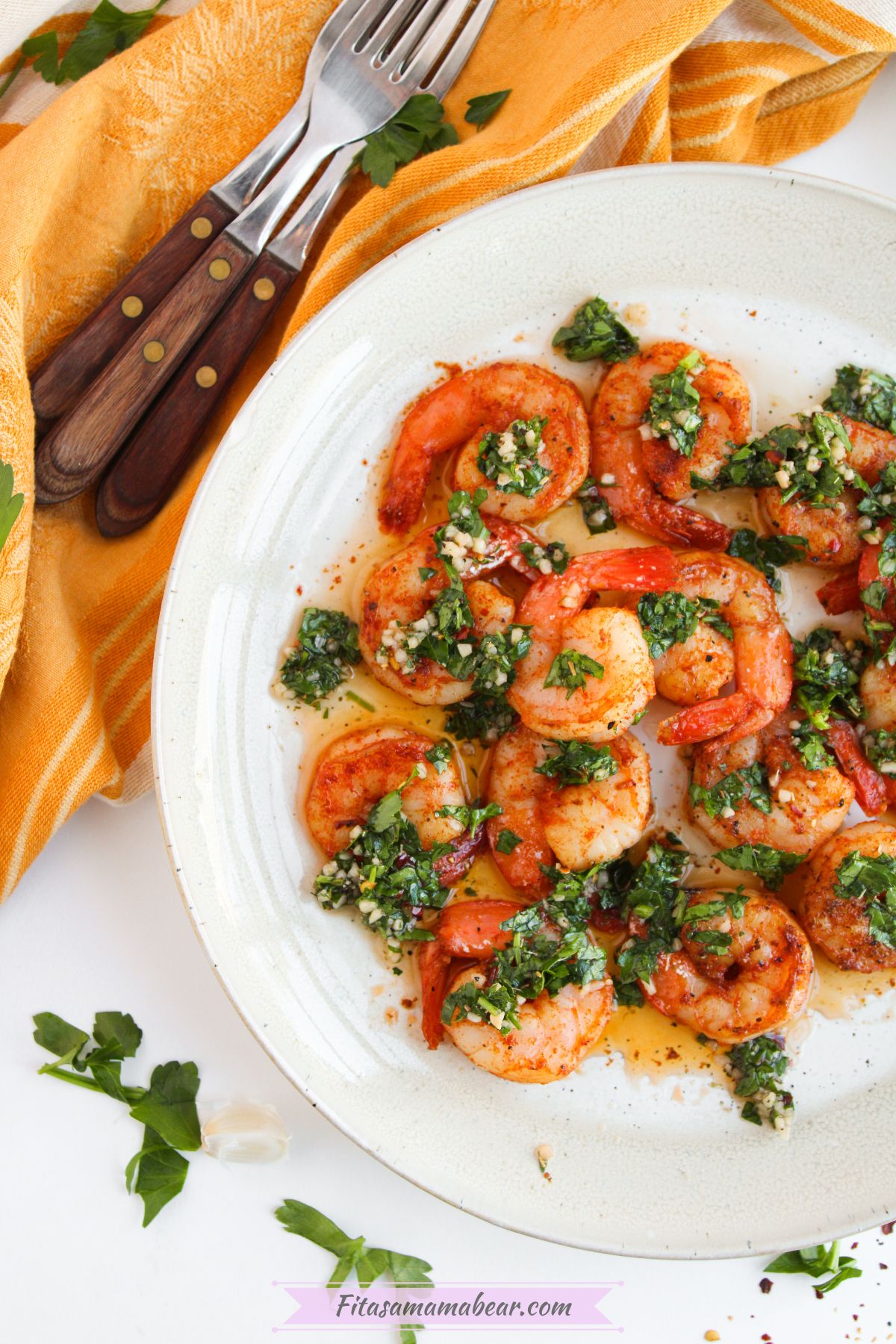 a plate of chimichurri shrimp with a set of forks on a kitchen towel at the side