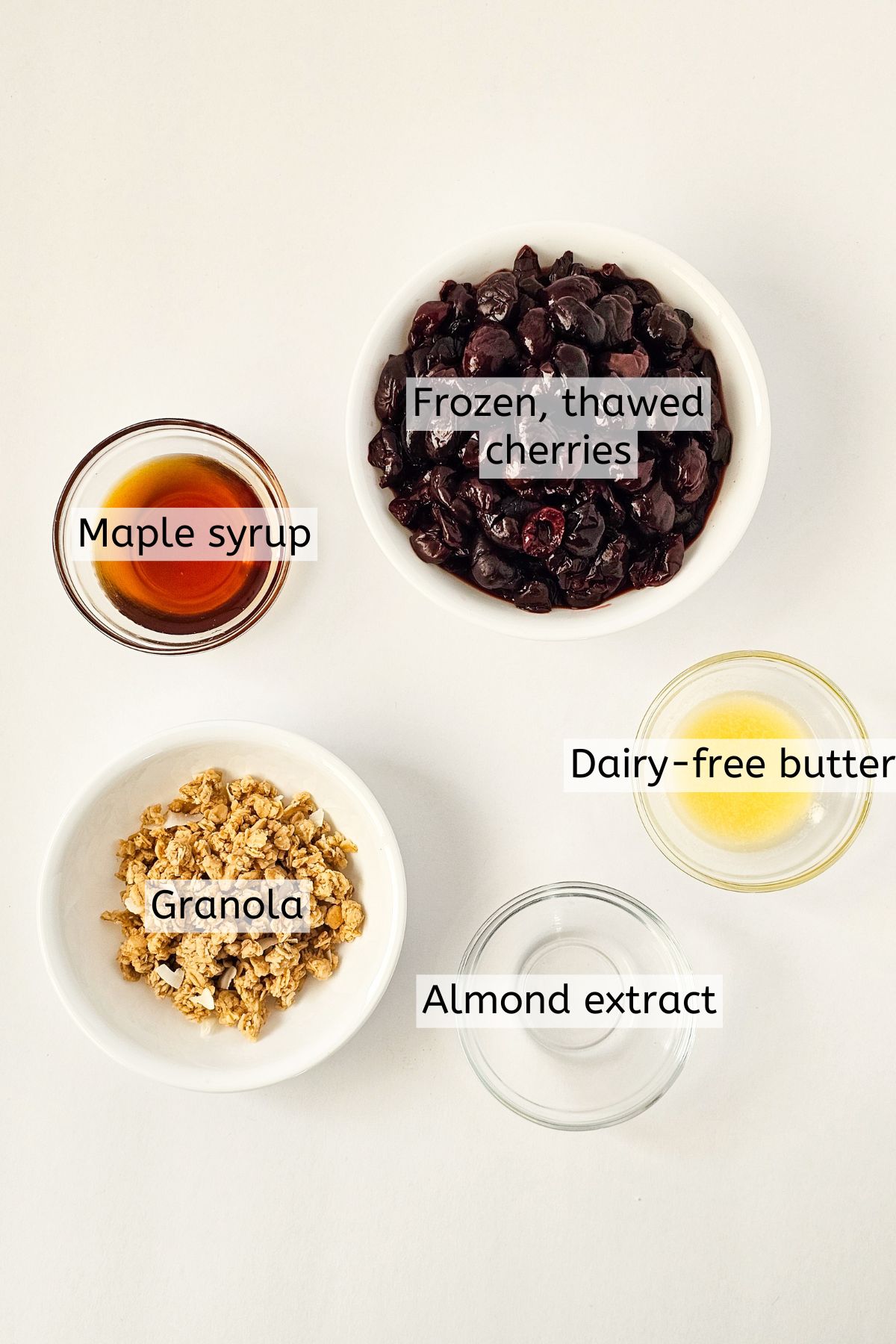 maple syrup, cherries, granola, dairy free butter, and almond extract with text on image