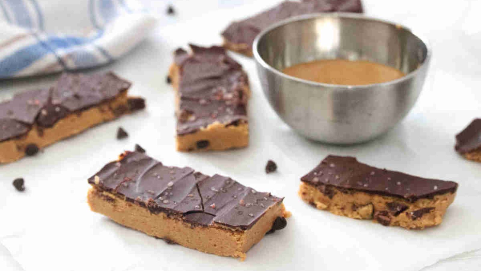 peanut butter chocolate protein bars with a bowl of peanut butter beside them
