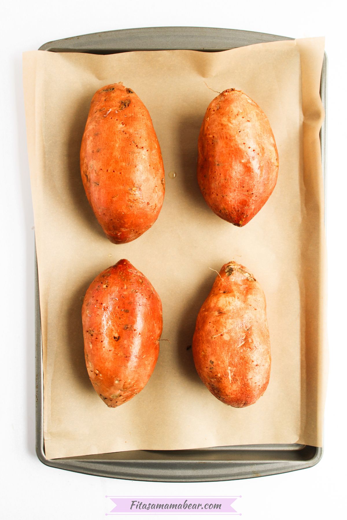 Four pieces of sweet potato lined up in a baking sheet.