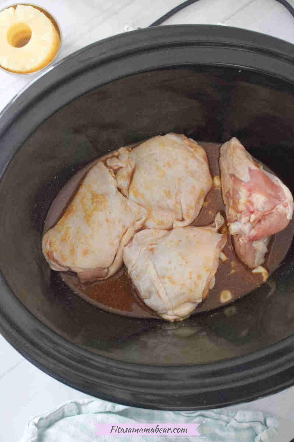 Mixed soy sauce, garlic, ginger, and broth with raw chicken inside the slow cooker.