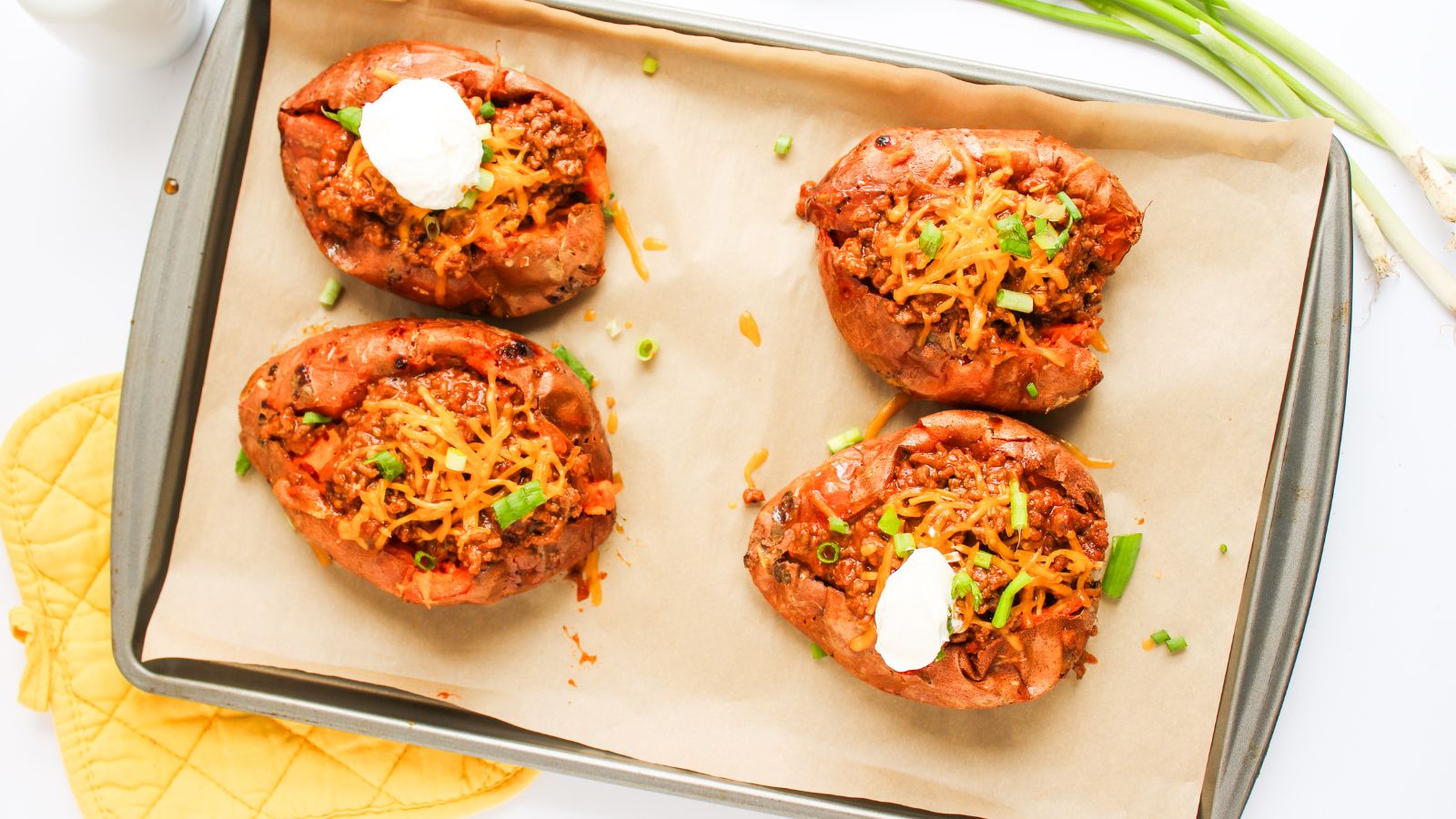 Baked sweet potatoes with Sloppy Joe stuffing on a baking tray.