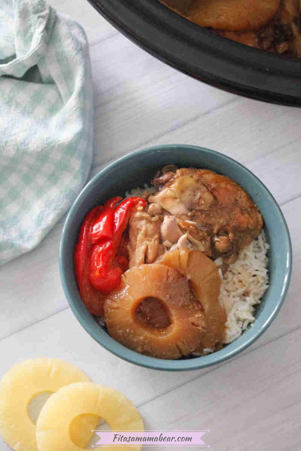 Slow cooker hawaiian chicken with pineapples and bell peppers on top of a bowl of rice.