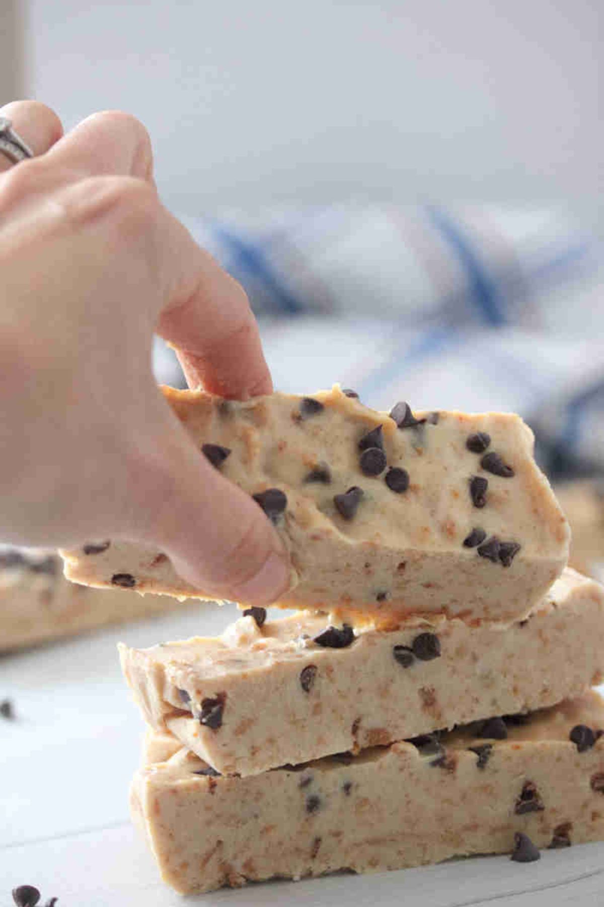A stack of frozen green yogurt bars with a hand taking one bar.