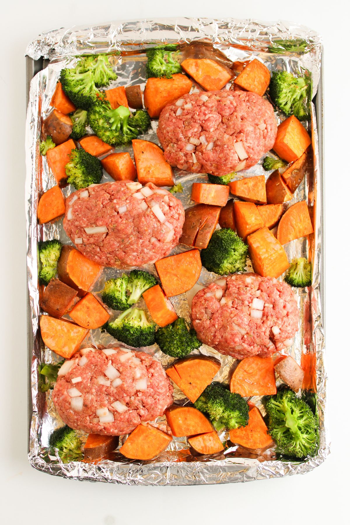 Ground beef meat loaves in a sheet pan with broccoli and sweet potatoes.