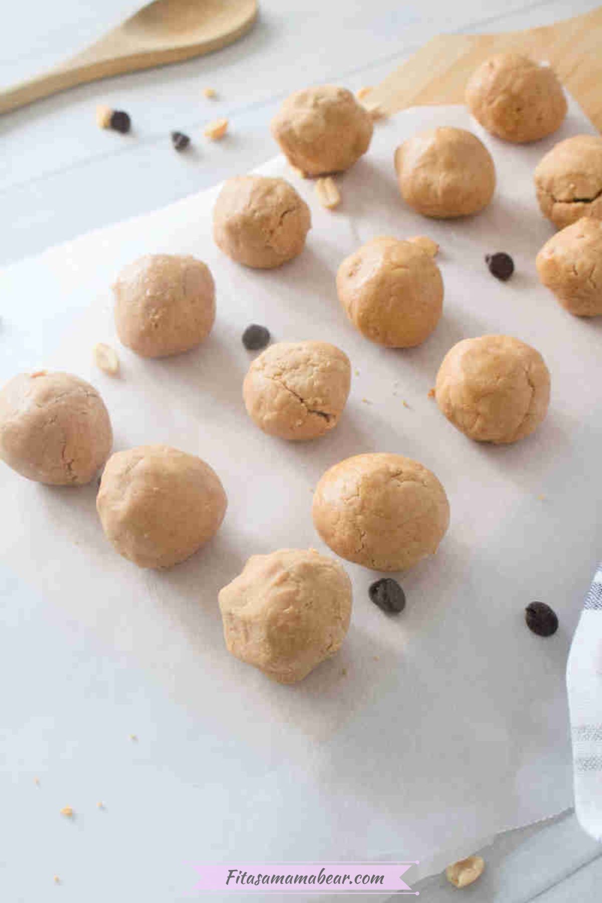 Peanut butter mix rolled into balls placed on top of a parchment paper.