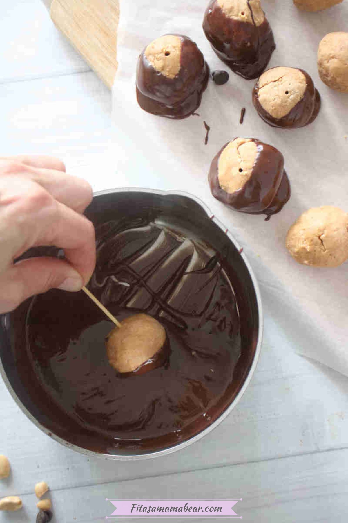 Peanut butter balls dipped on melted chocolate using a toothpick.