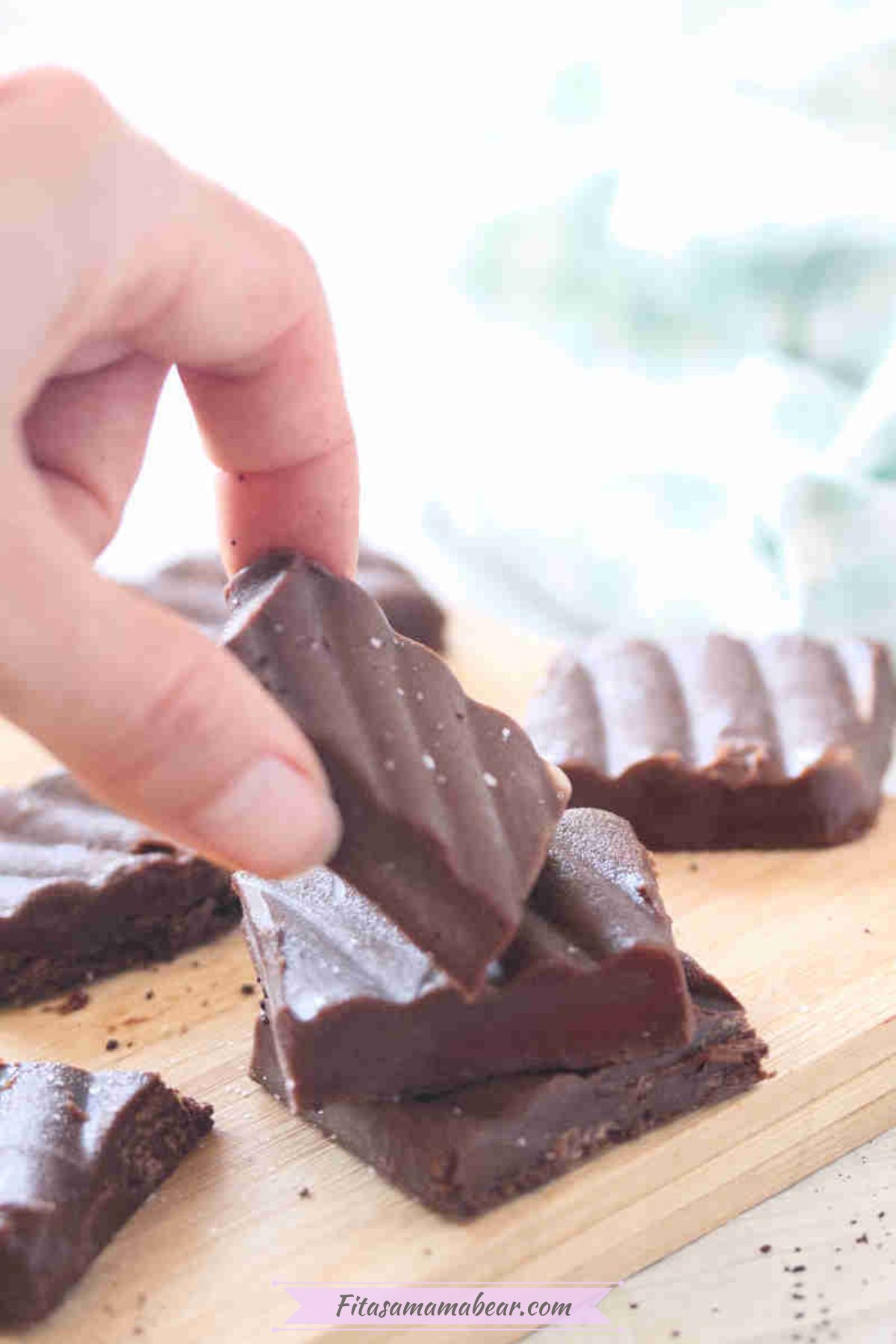 Square of coffee fudge being stacked on others on a cutting board.