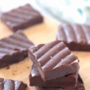 Squares of coffee fudge stacked and on on a cutting board.