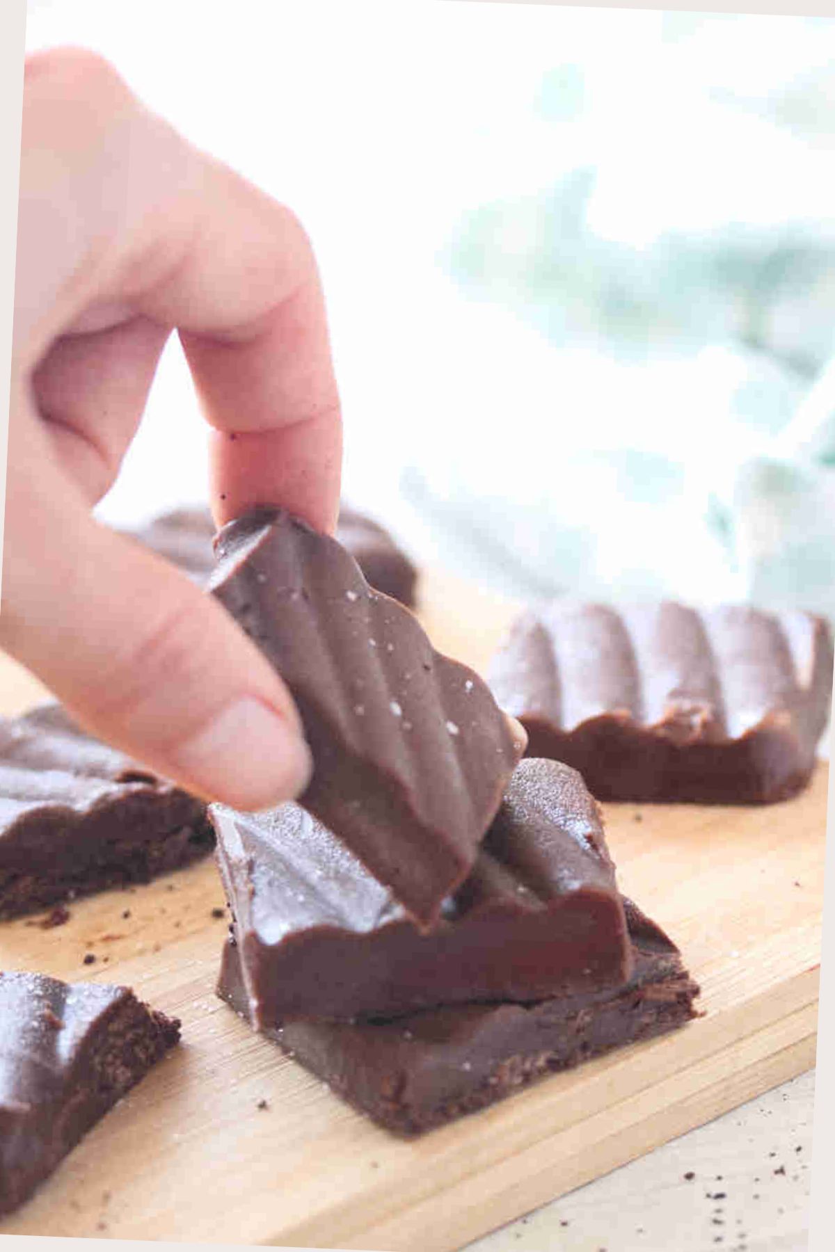 Square of coffee fudge being stacked on others on a cutting board.