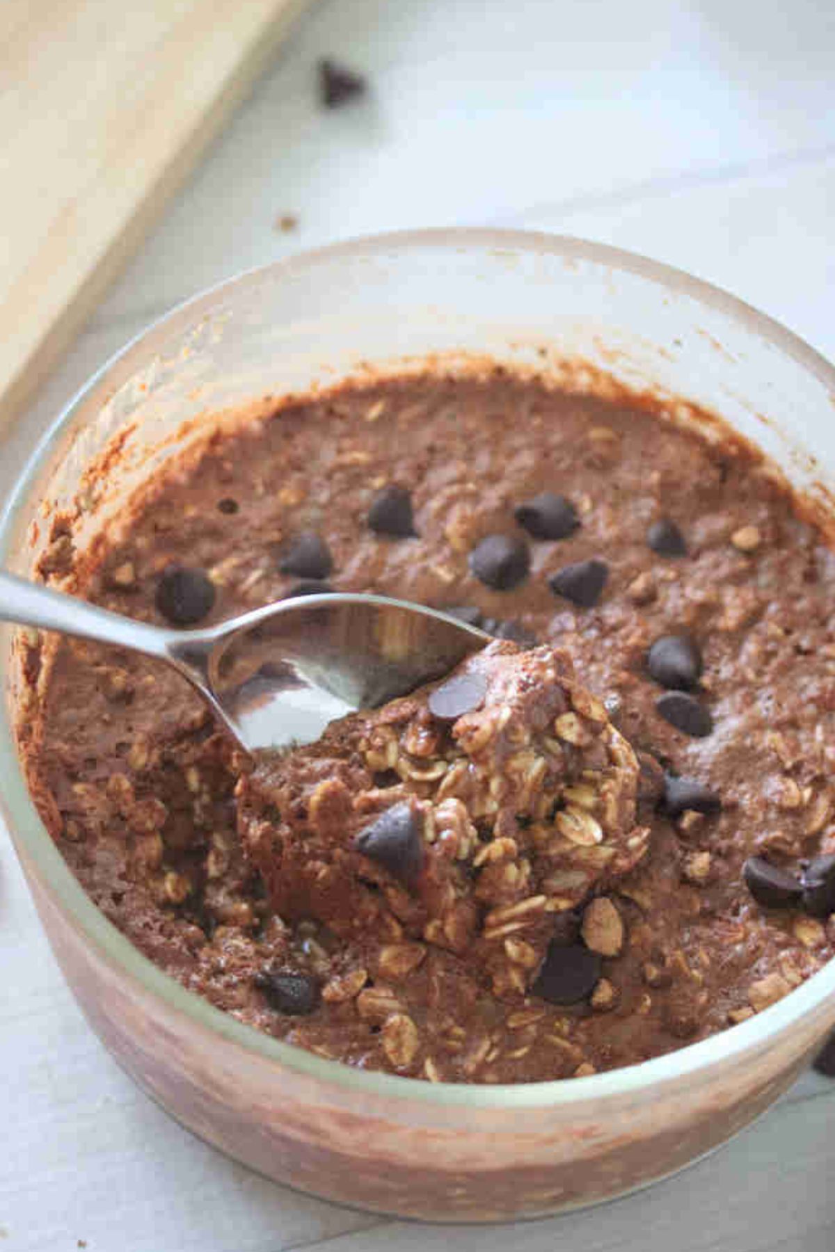Large bowl with chocolate protein overnight oats topped with chocolate chips and a spoon in the bowl.