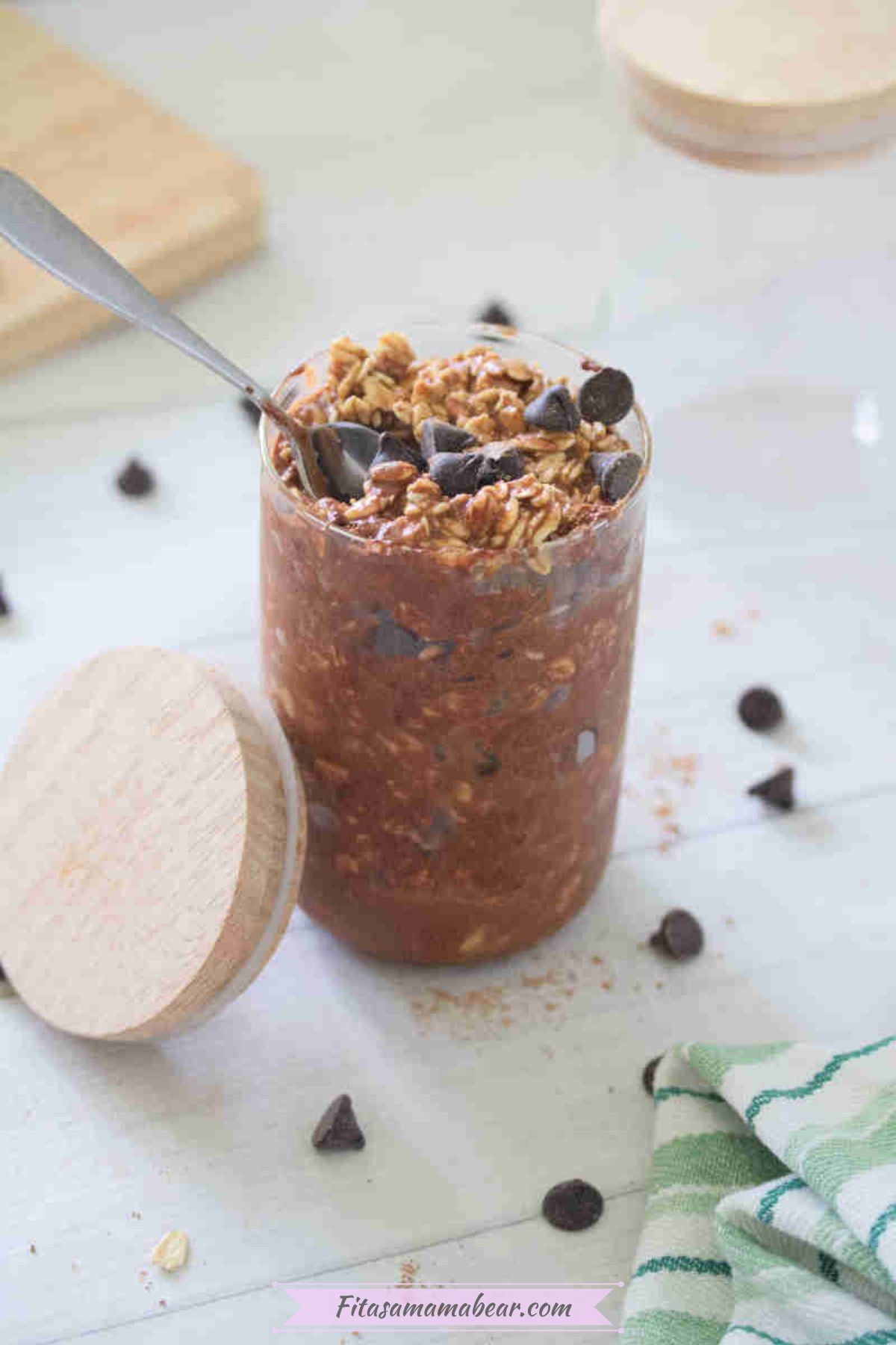 Small jar with chocolate protein overnight oats topped with chocolate chips and a lid beside it.