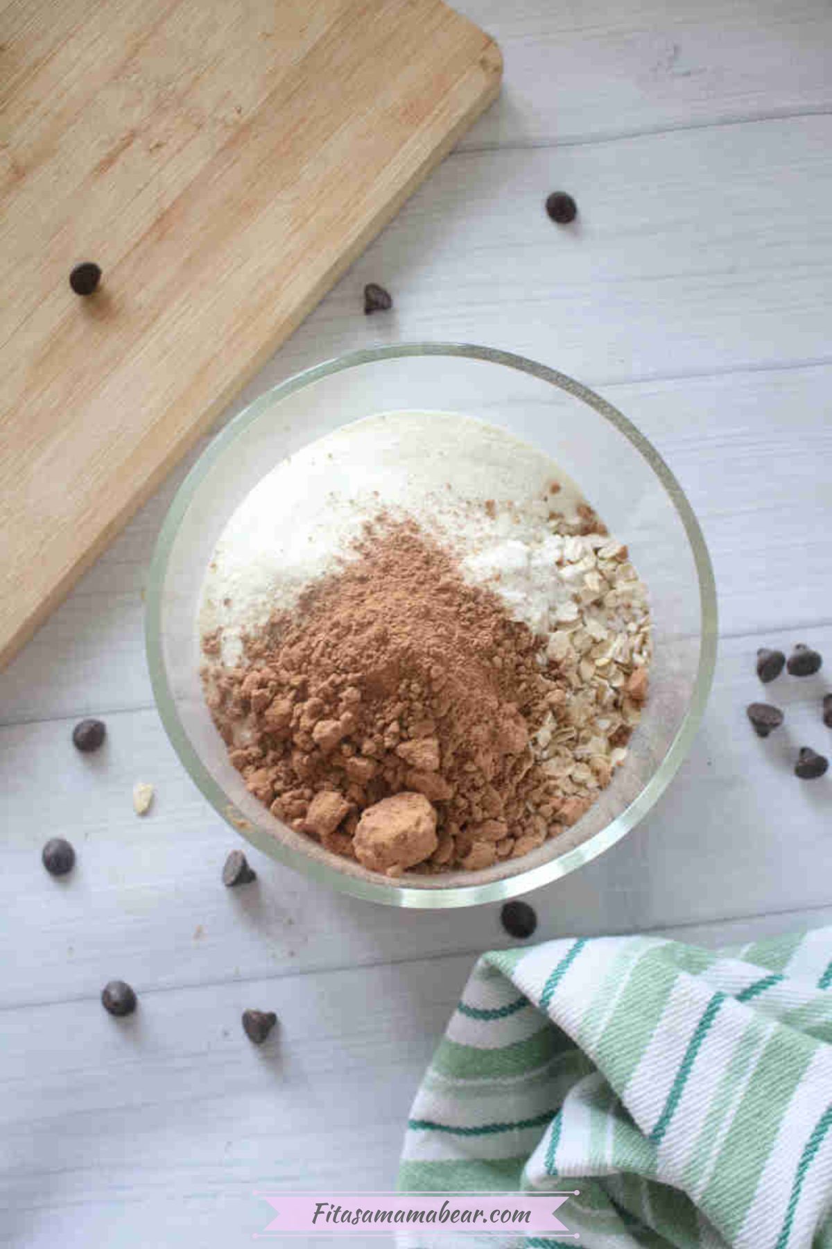 Glass bowl with cacao powder, oats, and collagen in it and chocolate chips around it.