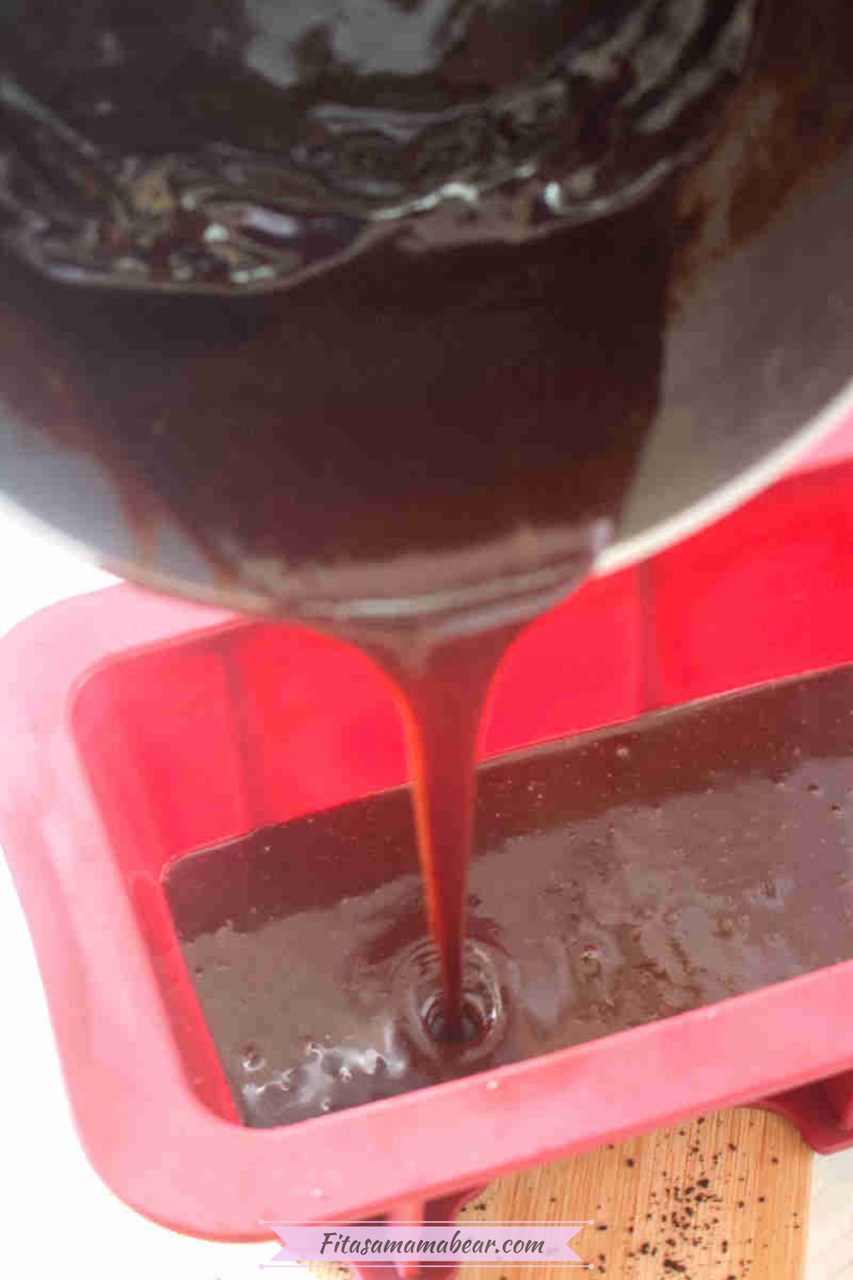 Chocolate being poured into a red silicone mold.
