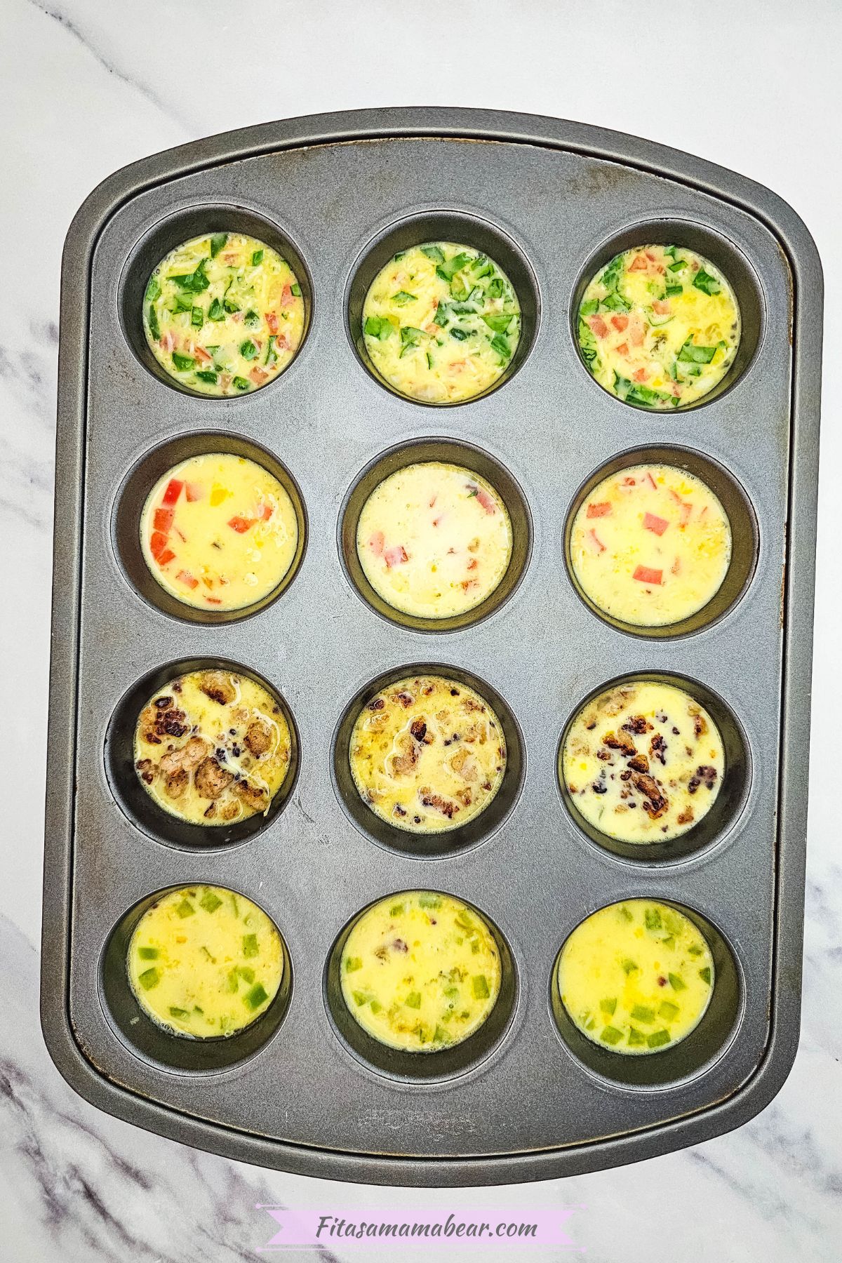 Uncooked mini omelets in a muffin tin.