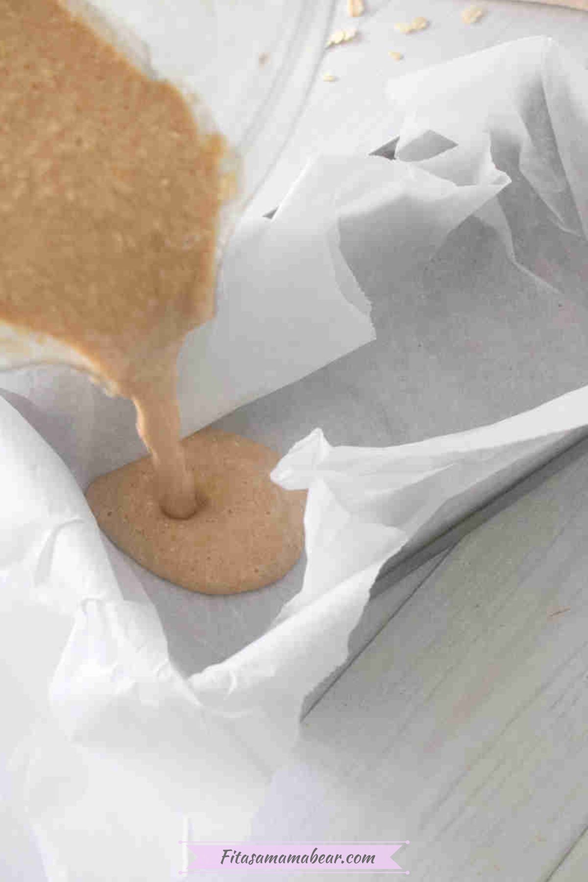 Blended ingredients being poured into a baking pan lined with parchment paper.