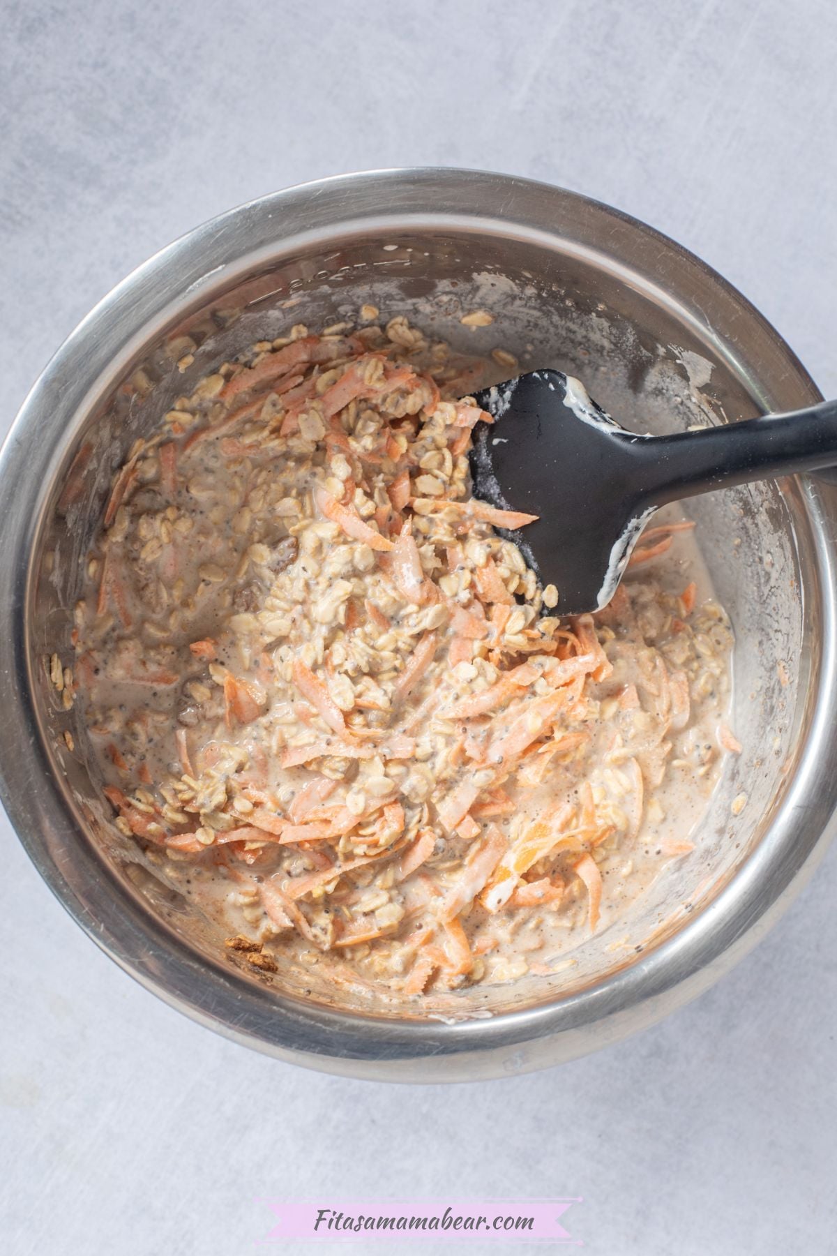 Steel bowl with raw overnight oats mixture in it and a black spatula.