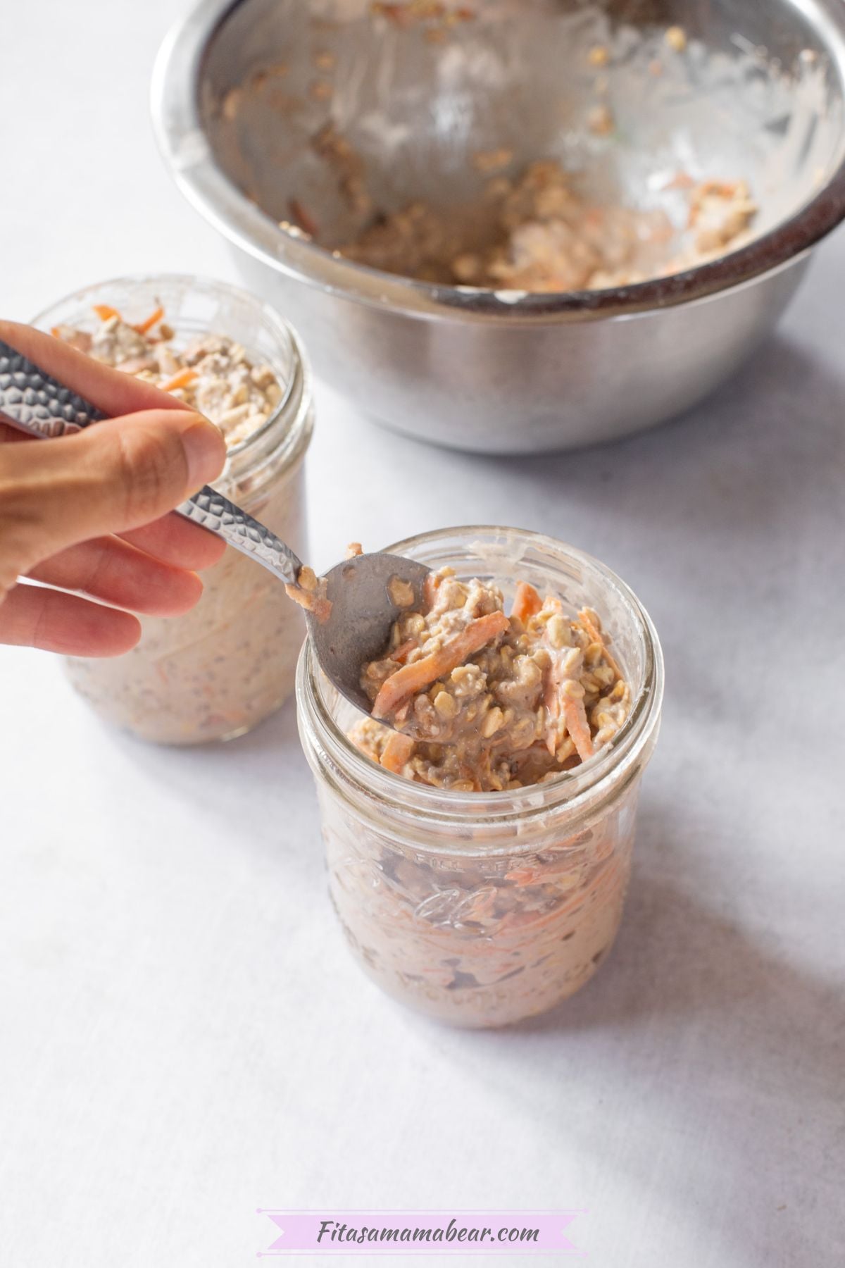 Two mason jars with carrot cake overnight oats being portioned into them with a spoon.