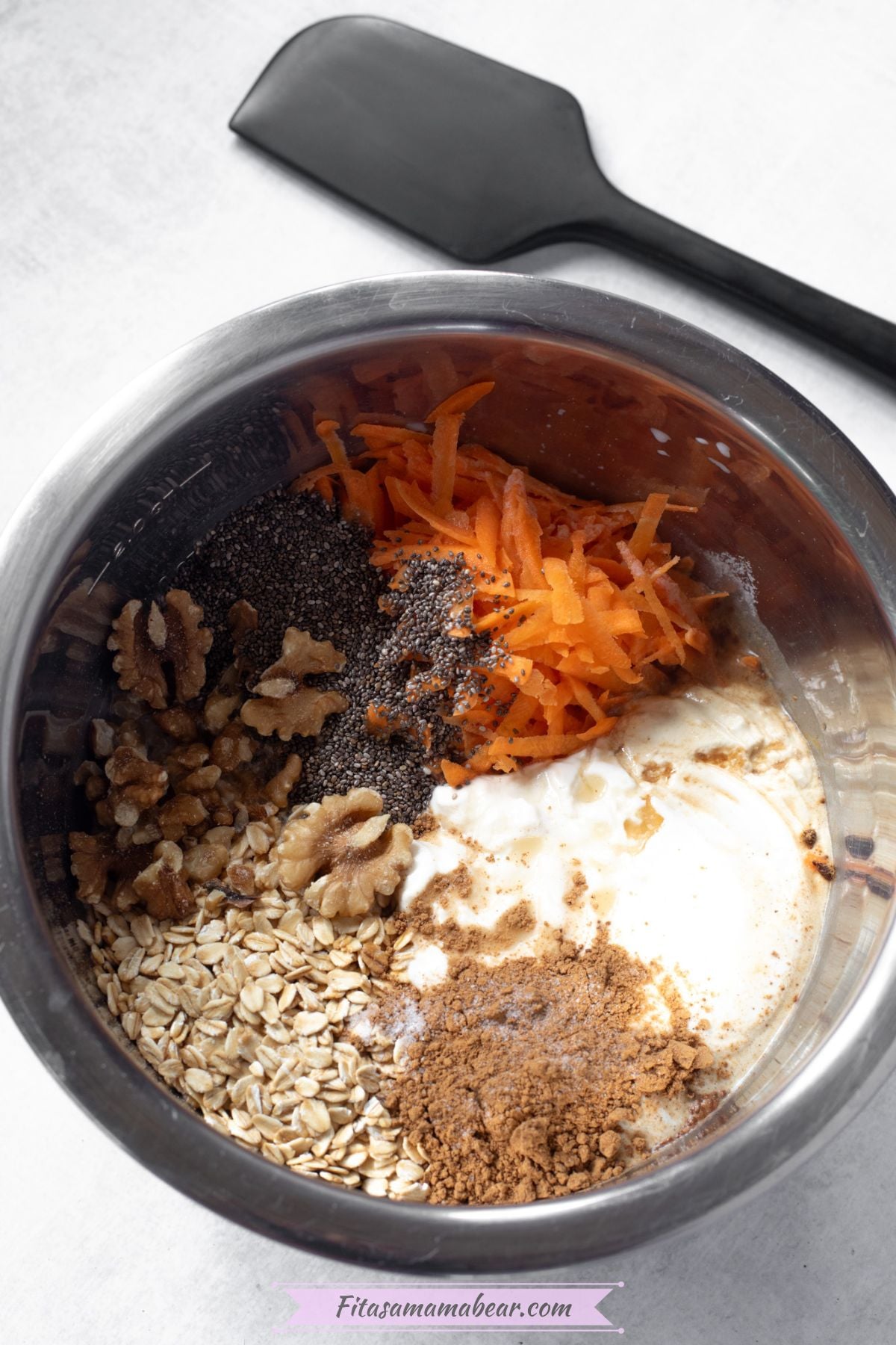 Steel bowl with oats, cinnamon, collagen, carrots, chia seeds, and walnuts in it.