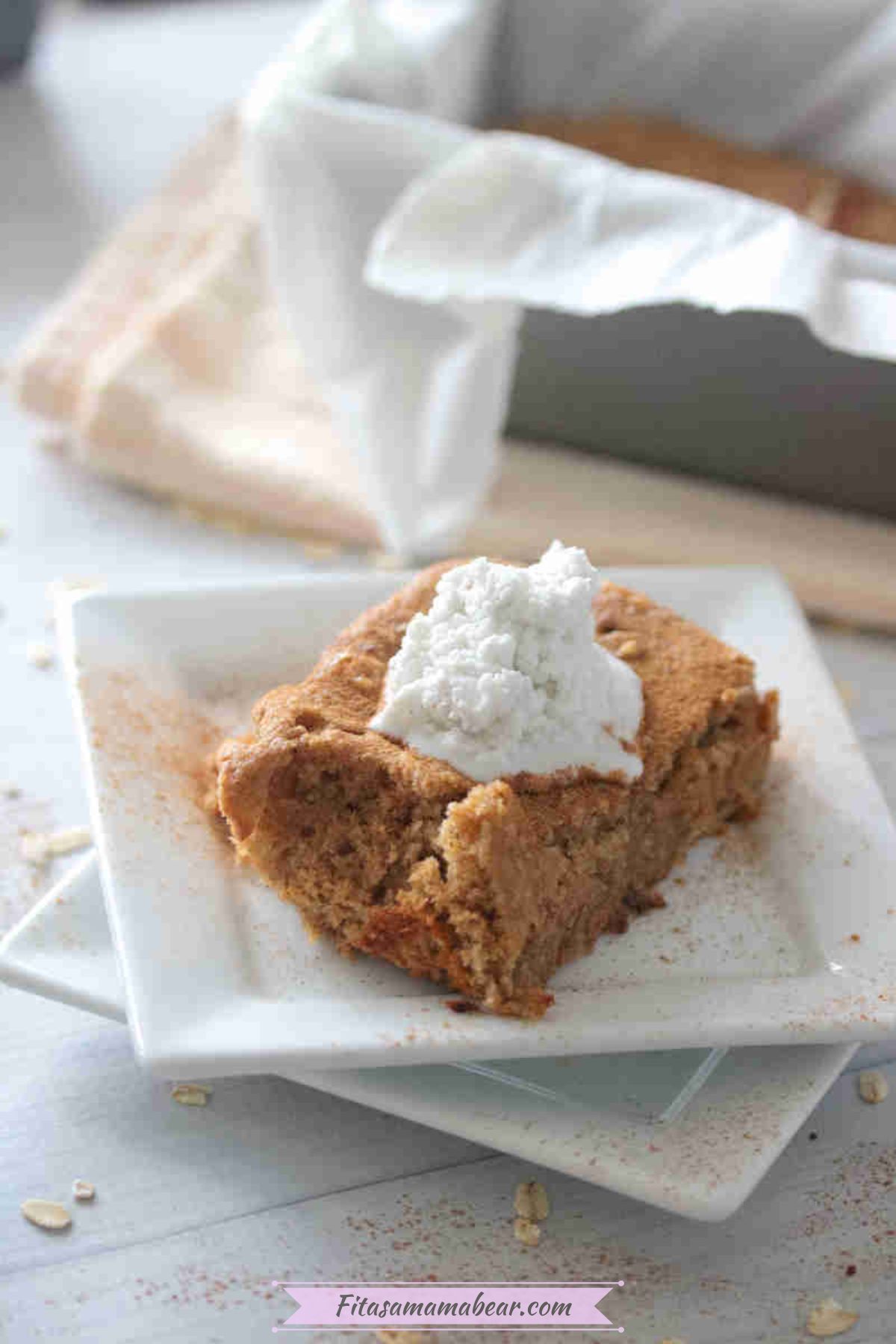 Sliced low calorie baked oats with a dollop of coconut cream on a white plate.