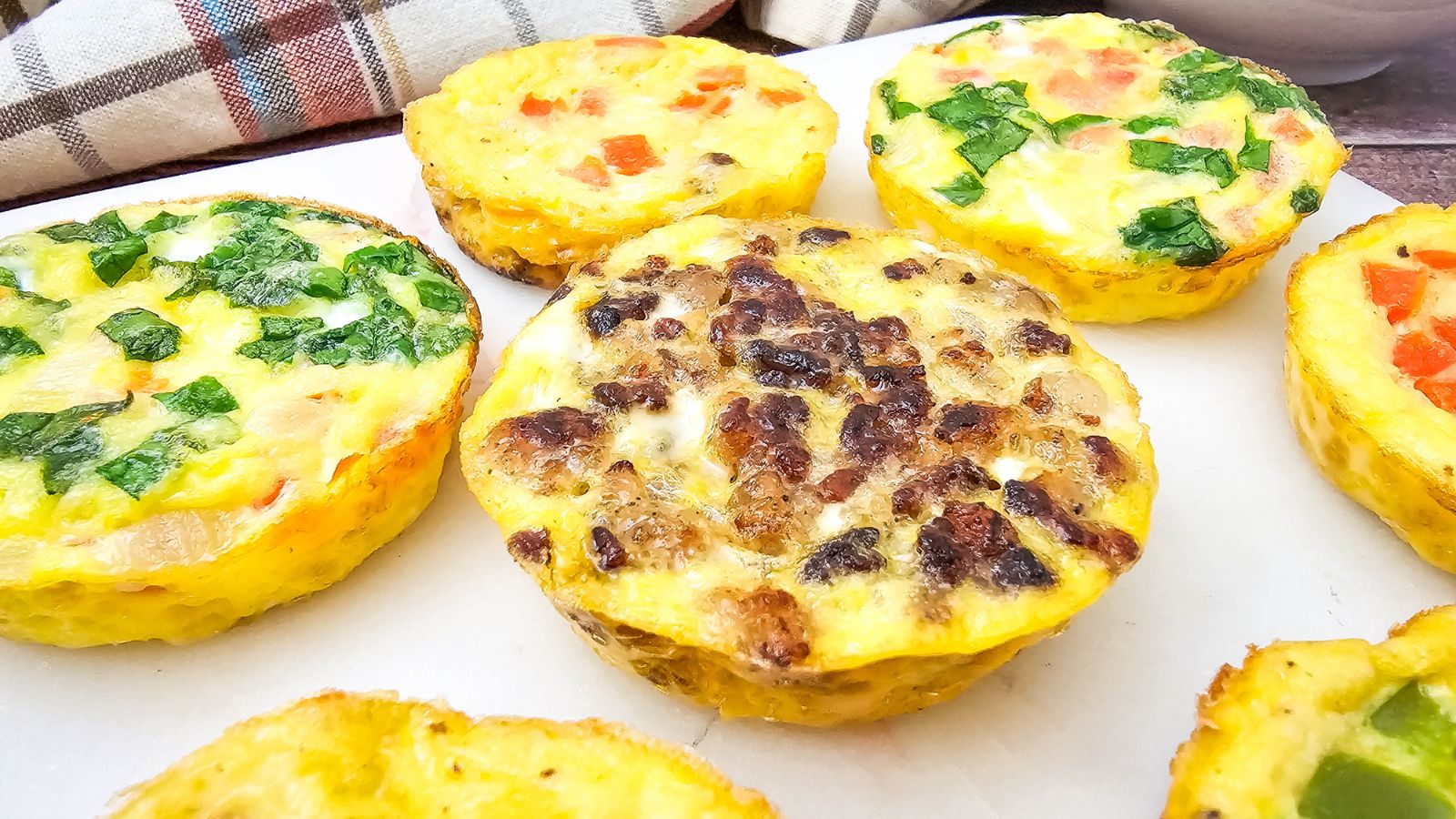 Mini dairy-free egg bites with bell peppers in them on a white plate.