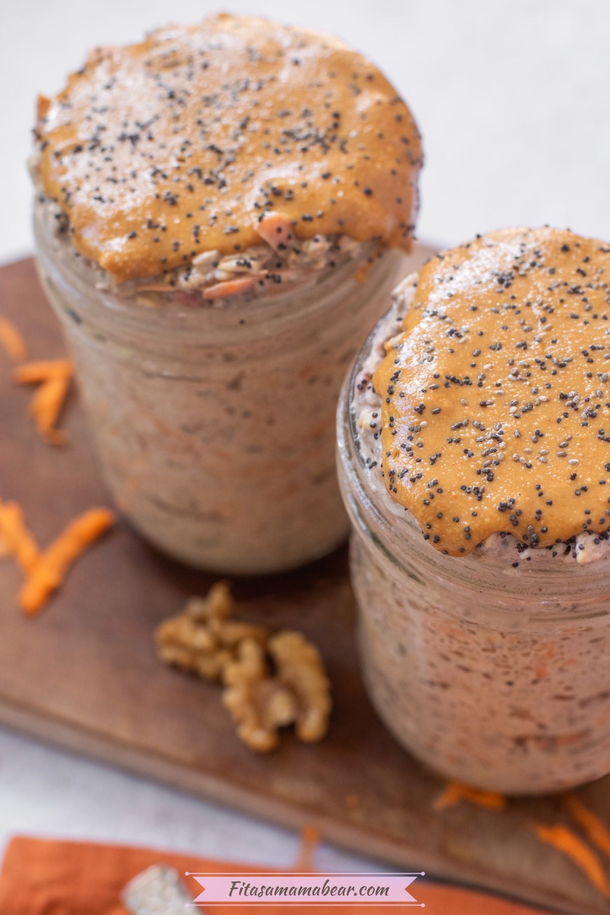 Two mason jars with carrot cake overnight oats topped with nut butter and chia seeds.