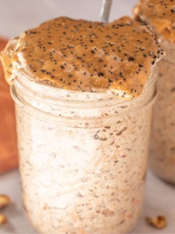 Mason jar with carrot cake overnight oats topped with nut butter and chia seeds.