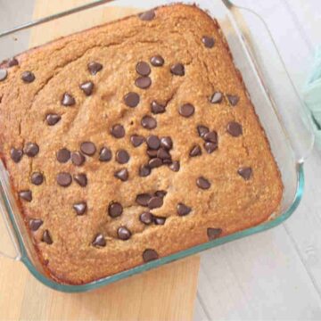 Baked pumkin oats with chocolate chips in a baking pan, placed on top of a wooden board.