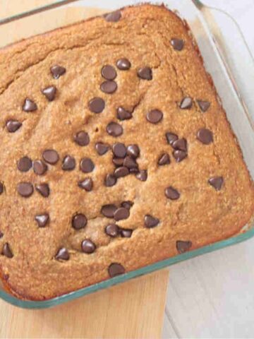 Baked pumkin oats with chocolate chips in a baking pan, placed on top of a wooden board.