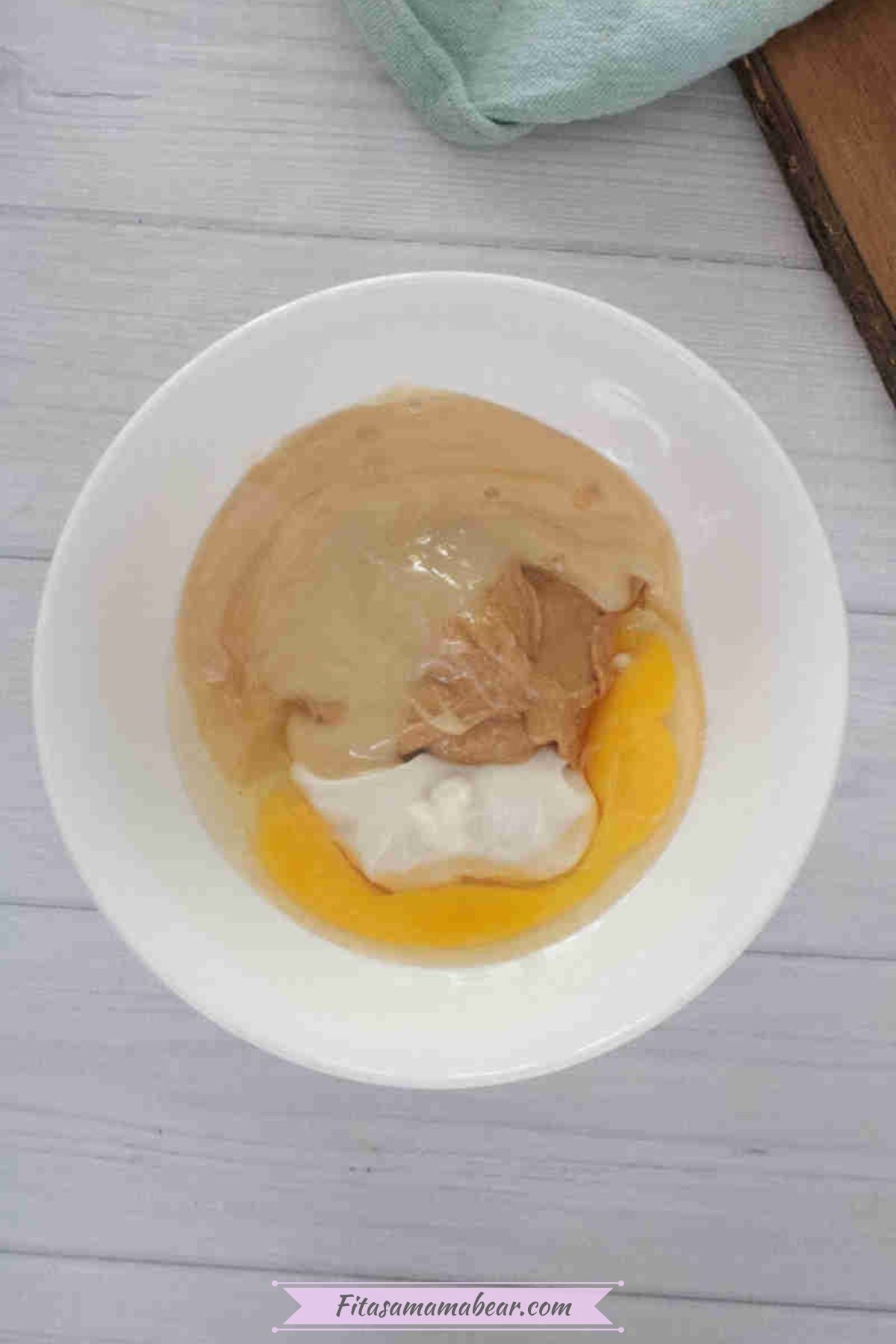 Egg, greek yogurt, peanut butter, and honey in a white bowl.