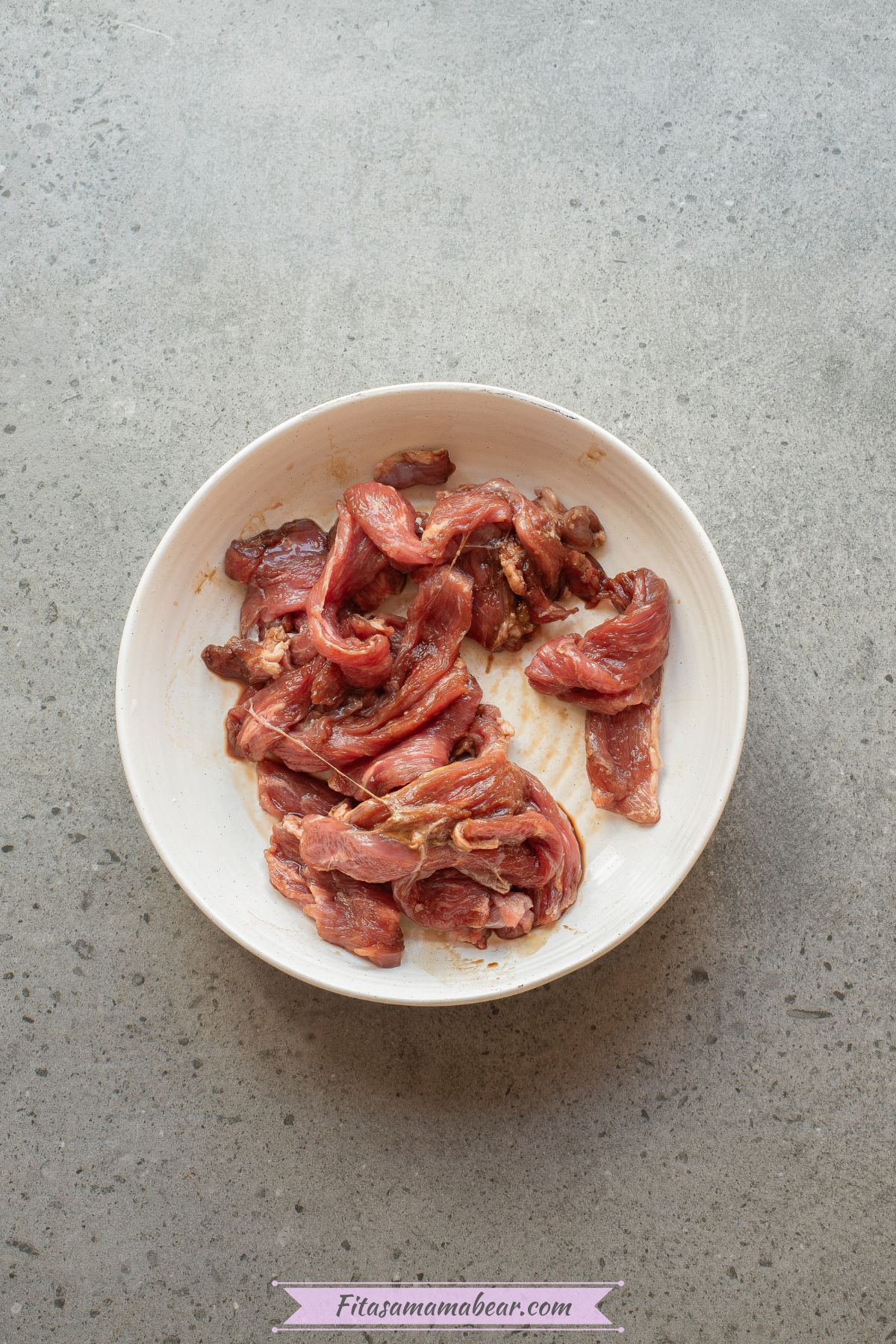 Beef strips, soy sauce, and arrowroot powder mixed in a bowl.
