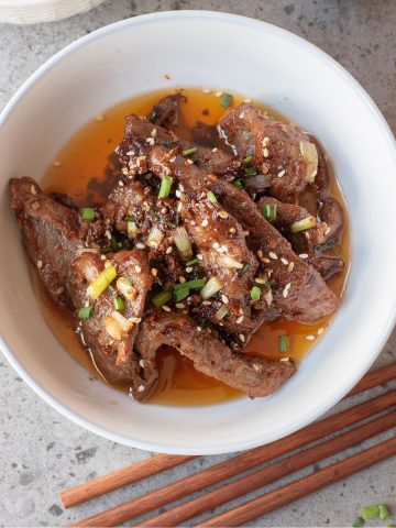 Hot and spicy stir fried beef strips in a white bowl.