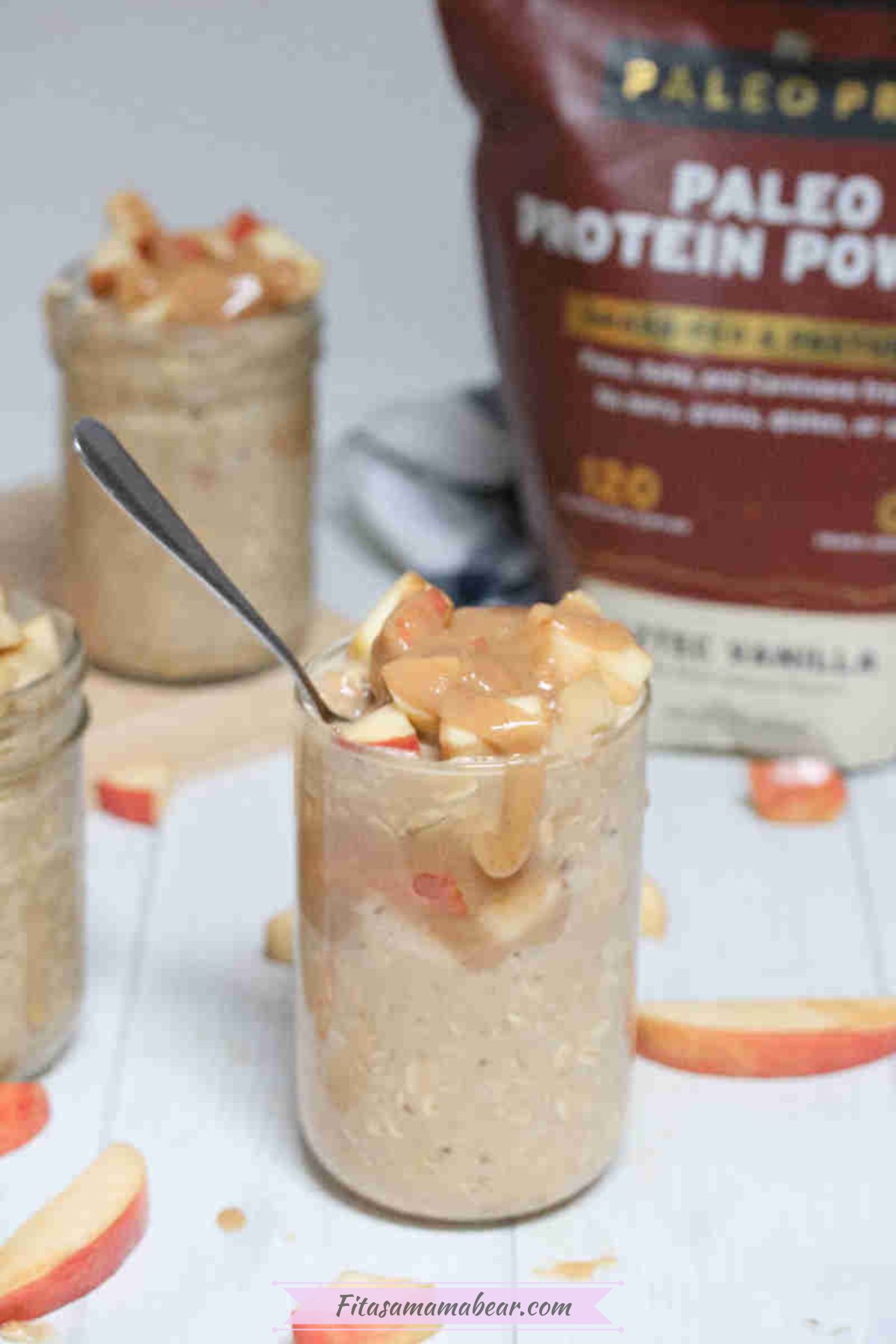 Caramel apple overnight oats in mason jars topped with homemade caramel and apples and protein powder in the back.