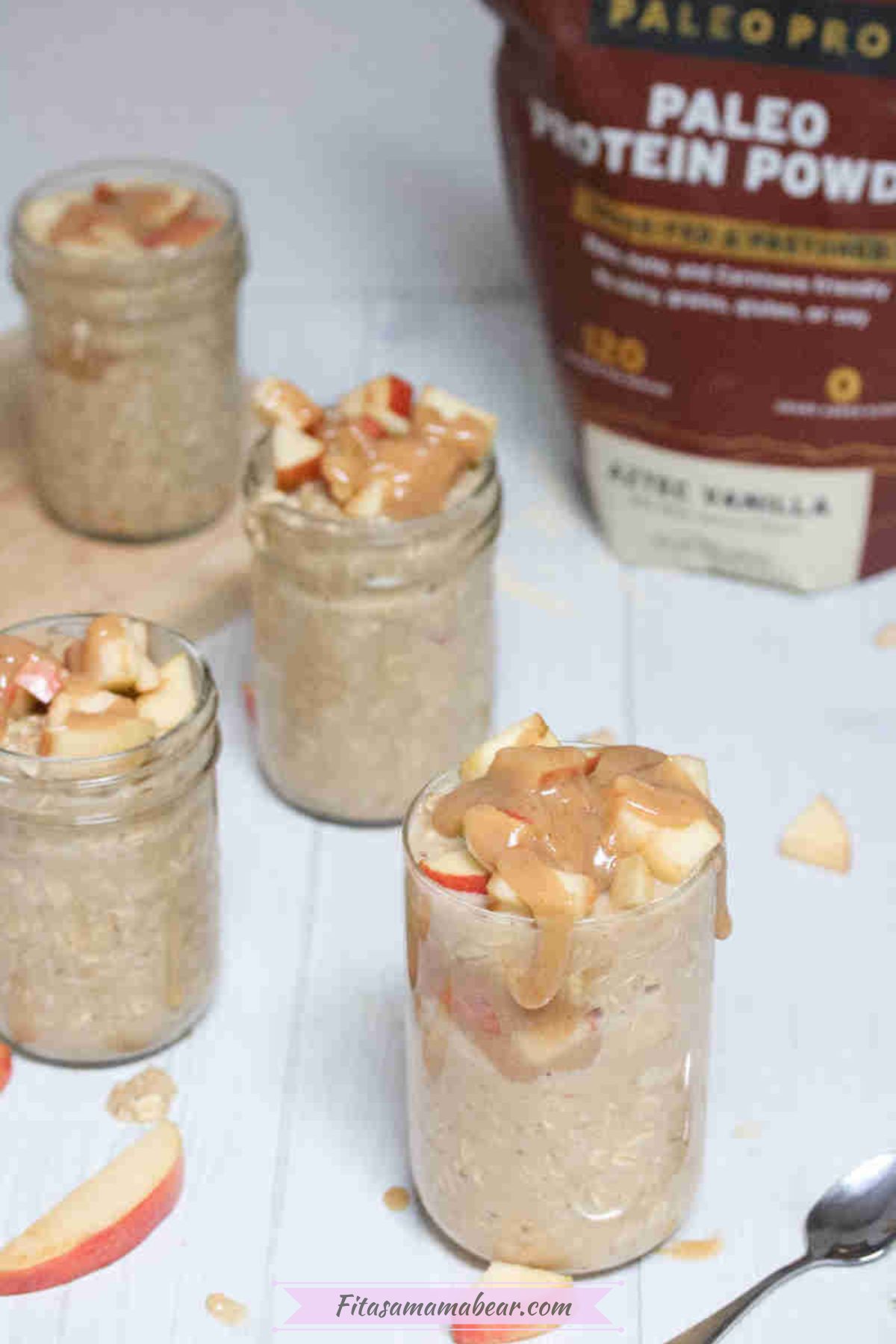 Caramel apple overnight oats in mason jars topped with homemade caramel and apples and protein powder in the back.