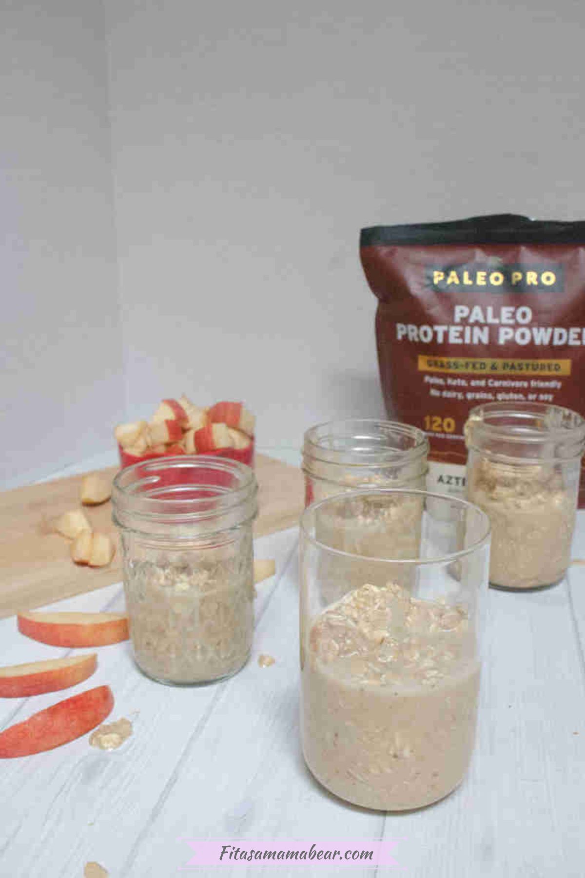Mason jars half filled with caramel apple overnight protein oats with apples and protein powder around them.
