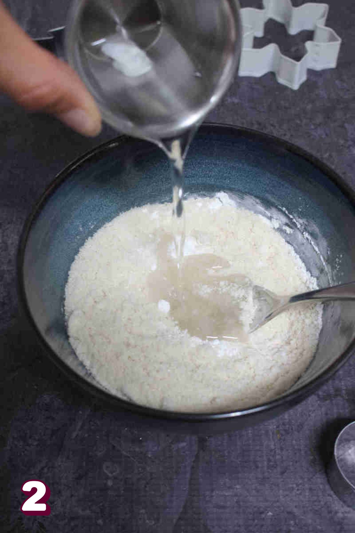 Coconut oil being poured into a bowl of almond flour.