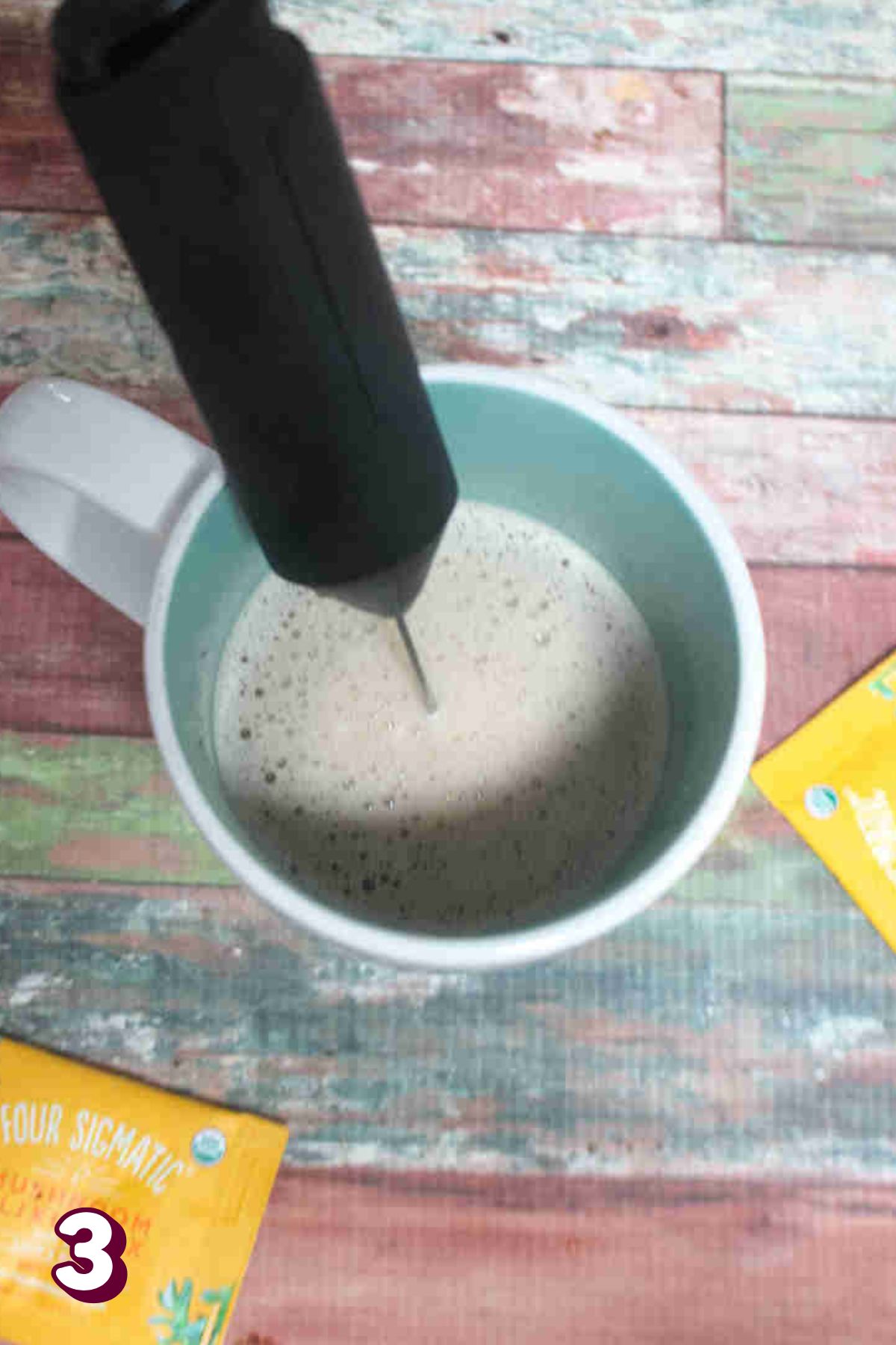 Handheld frother in a white mug with a matcha latte in it,