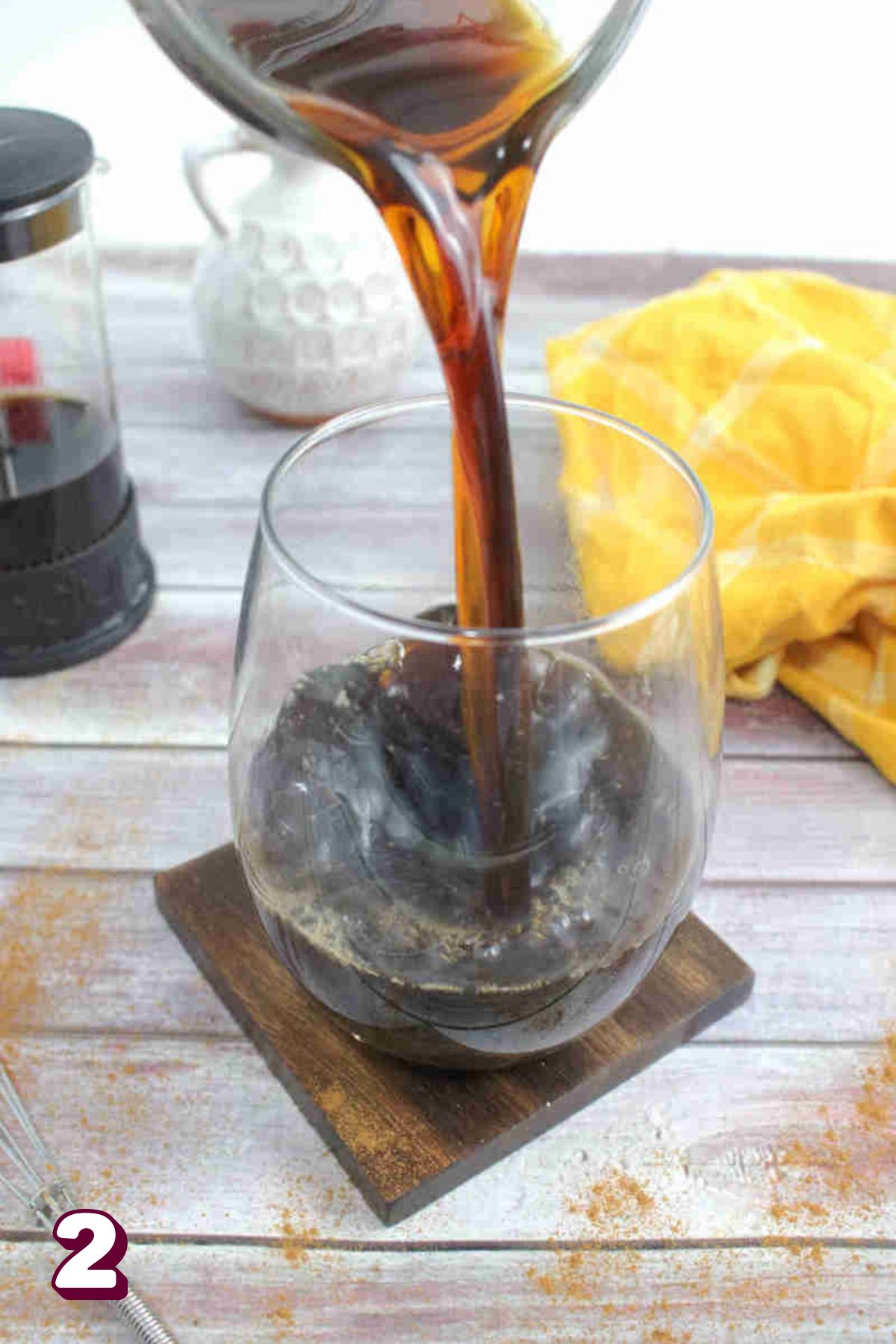 Coffee being poured into a glass on a coaster.